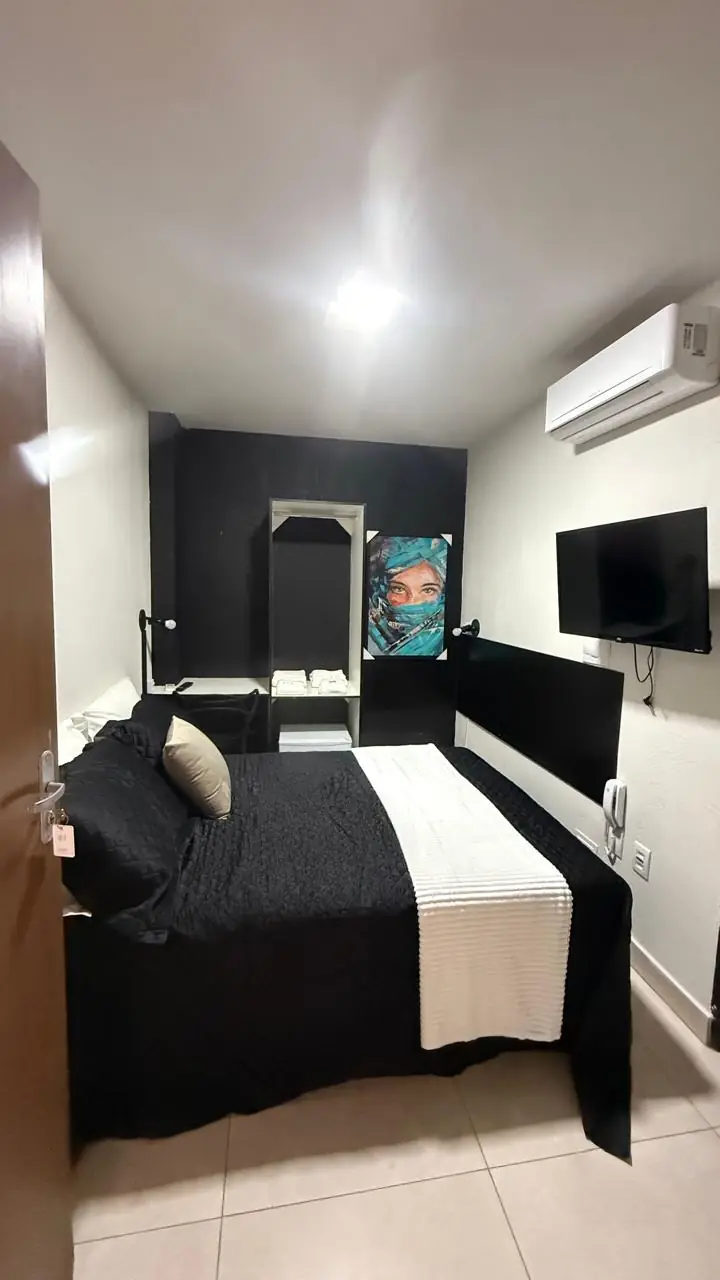 Suíte com televisão, espelho e quadro
