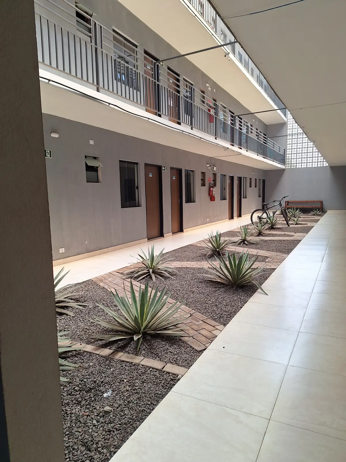 Corredor externo de acesso às suítes do Hotel SIGA, com canteiro de plantas